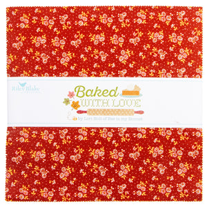 A folded fabric bundle with a red background and a white center band printed with the text 'Baked WITH LOVE' and 'by Lori Hall of Bew in my Beecher.' The fabric has a repeating floral and leaf pattern in yellow, orange, and white.