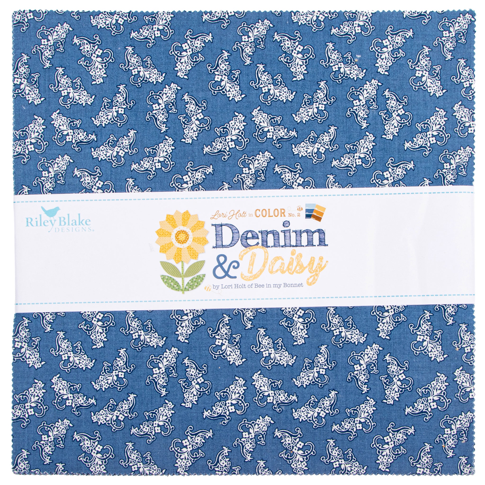 A folded fabric swatch with a blue denim-like background and a repeating white floral and scroll pattern, wrapped with a white paper label that reads Riley Blake Designs and Denim & Daisy.