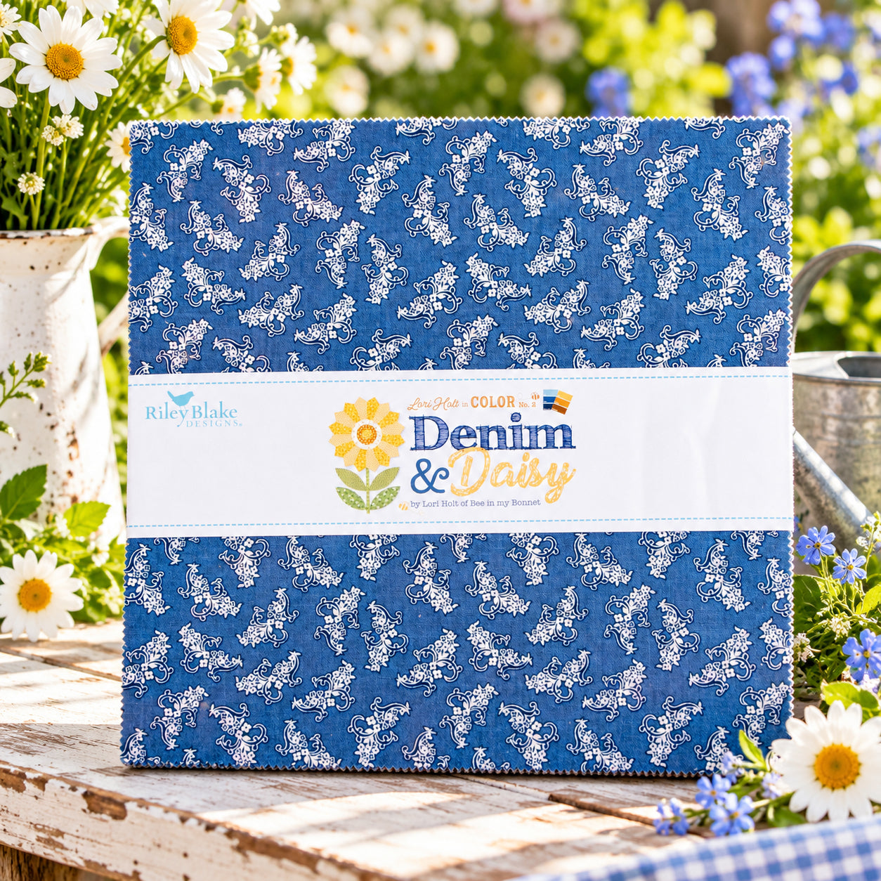A quilted fabric bundle wrapped in a white paper band. The fabric has a medium blue background with a white floral vine print.