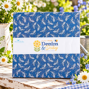 A quilted fabric bundle wrapped in a white paper band. The fabric has a medium blue background with a white floral vine print.