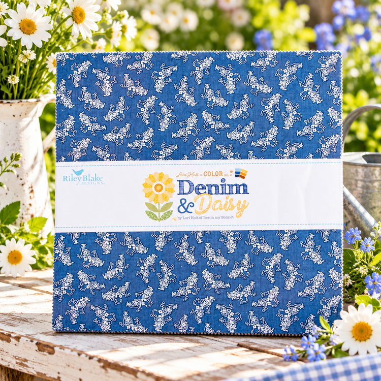 A quilted fabric bundle wrapped in a white paper band. The fabric has a medium blue background with a white floral vine print.