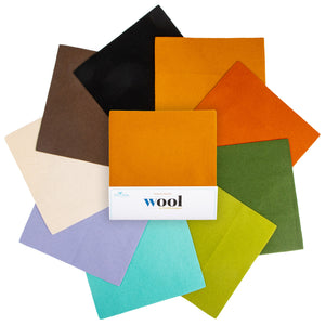 An arrangement of wool fabric swatches in assorted colors, including black, brown, cream, orange, green, purple, turquoise, and lime green, with a white paper band labeled 'wool' across the center.