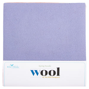 A square fabric labeled 'Spring Bundle Wool' by Riley Blake, showing a soft lavender-purple wool texture above a white printed label.