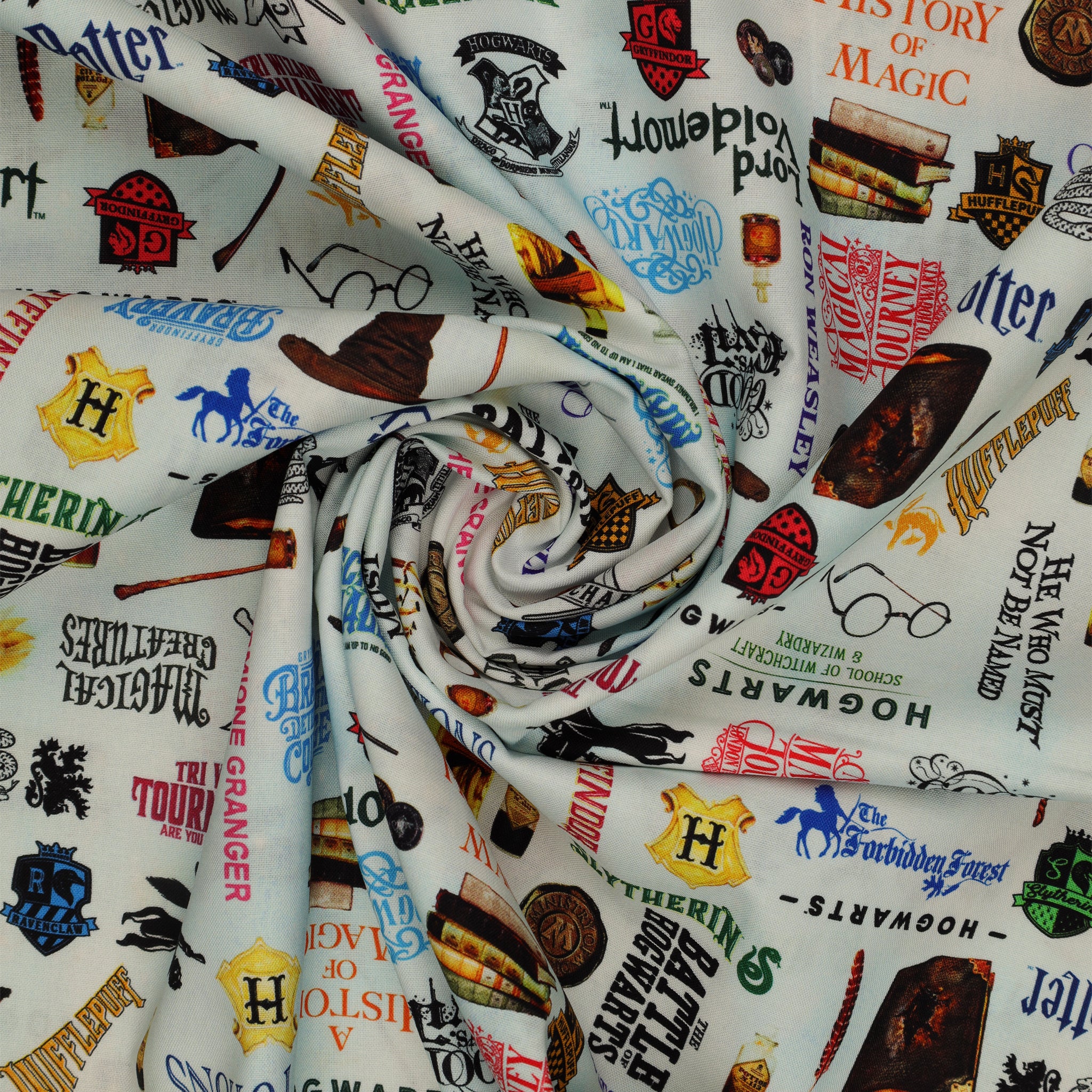 Pale blue Harry Potter fabric with multicolored words, house crests, books, potion bottles, wands and spectacles in a swirl.