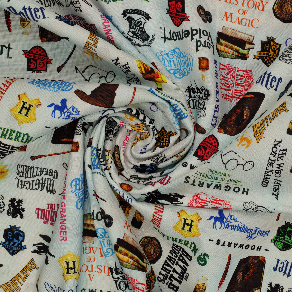 Pale blue Harry Potter fabric with multicolored words, house crests, books, potion bottles, wands and spectacles in a swirl.