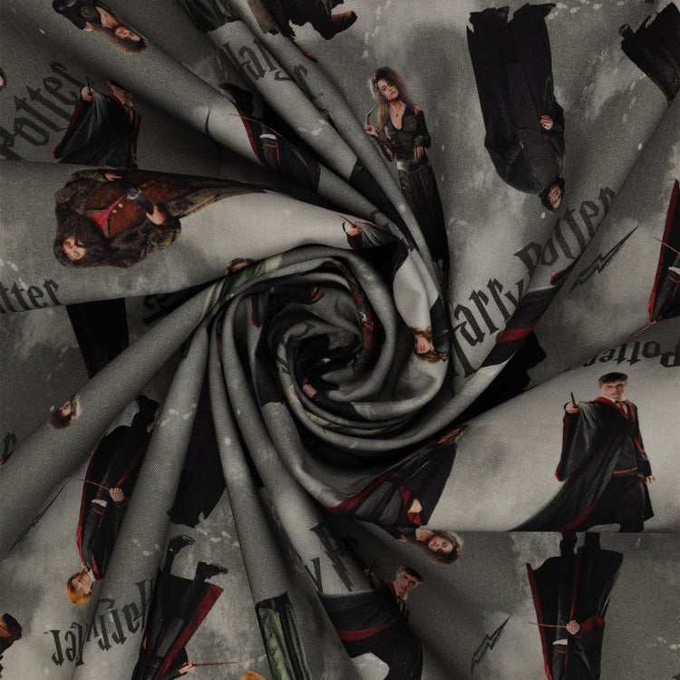 Gray Harry Potter fabric with scattered robed film figures, black logos, lightning bolts and pale footprints in a swirl.