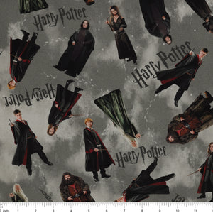 Gray Harry Potter fabric with scattered robed film figures, black logos, lightning bolts and pale footprints with ruler for scale.
