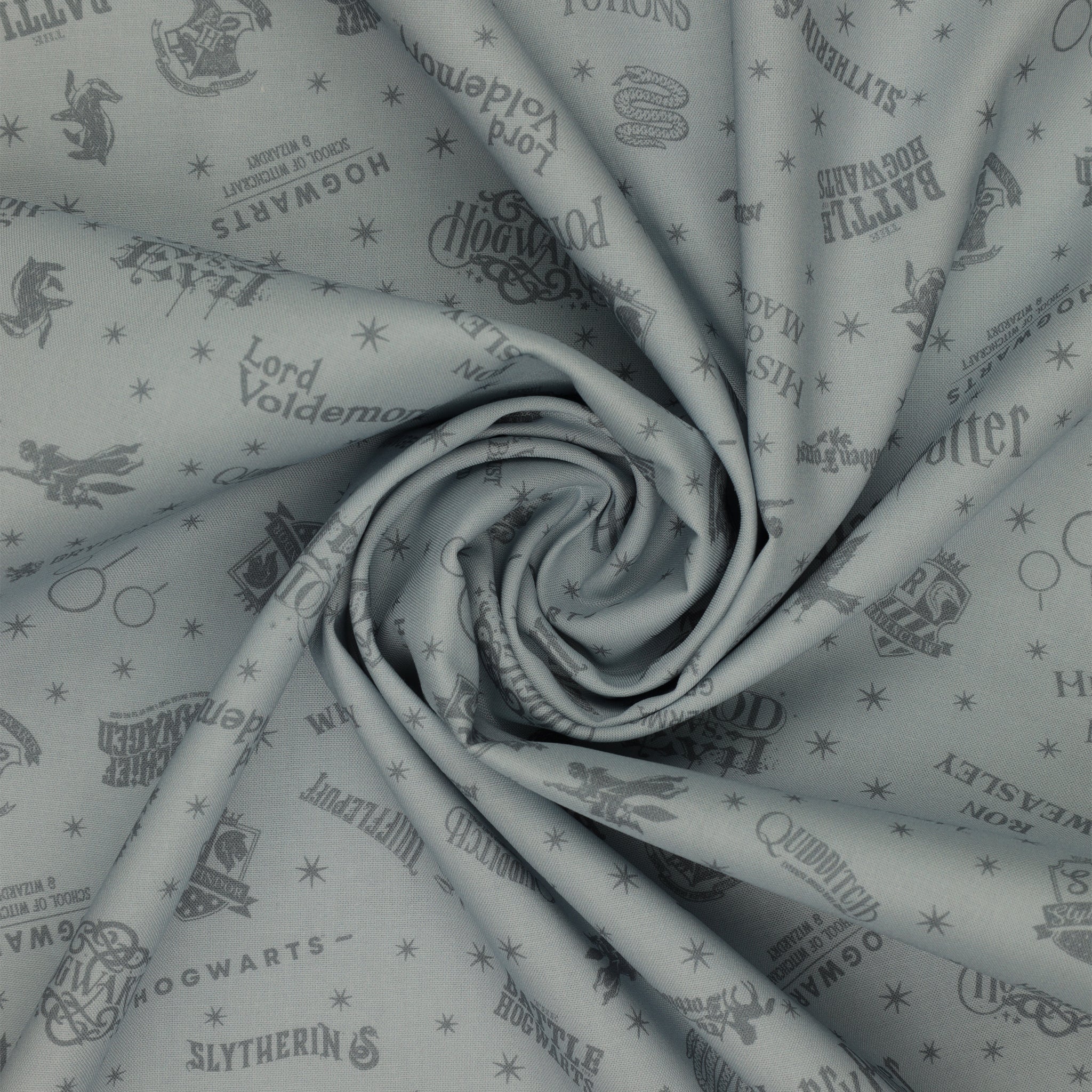 Light gray Harry Potter fabric with darker gray lettering, Hogwarts crests, magical icons and stars in a swirl.