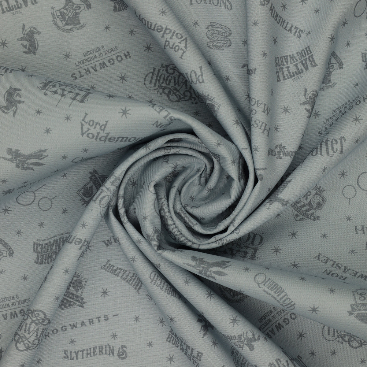 Light gray Harry Potter fabric with darker gray lettering, Hogwarts crests, magical icons and stars in a swirl.
