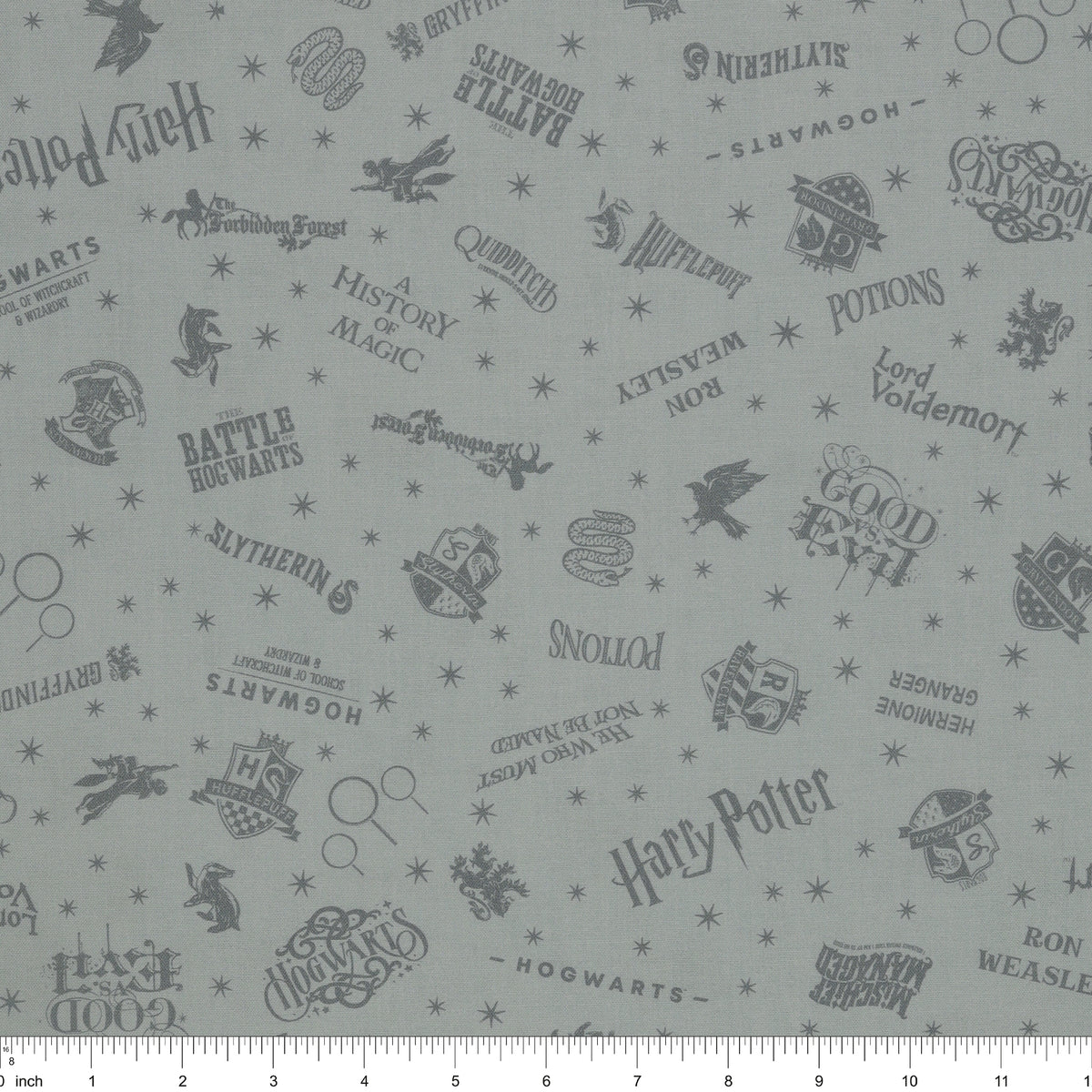 Light gray Harry Potter fabric with darker gray lettering, Hogwarts crests, magical icons and stars with ruler for scale.