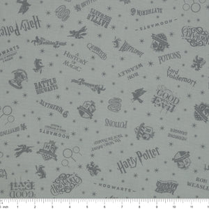 Light gray Harry Potter fabric with darker gray lettering, Hogwarts crests, magical icons and stars with ruler for scale.