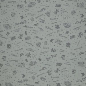 Light gray Harry Potter fabric with darker gray lettering, Hogwarts crests, magical icons and stars.