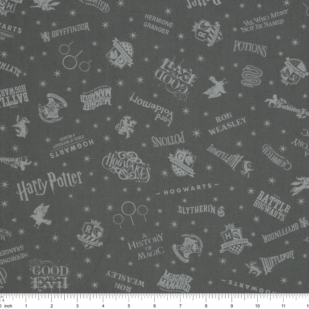 Charcoal Harry Potter fabric with pale gray words, house crests, Quidditch goalposts and stars with ruler for scale.