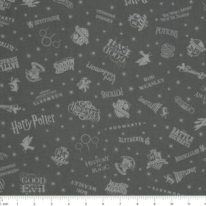 Charcoal Harry Potter fabric with pale gray words, house crests, Quidditch goalposts and stars with ruler for scale.