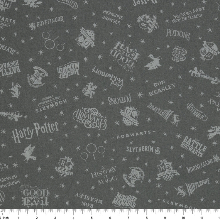 Charcoal Harry Potter fabric with pale gray words, house crests, Quidditch goalposts and stars with ruler for scale.