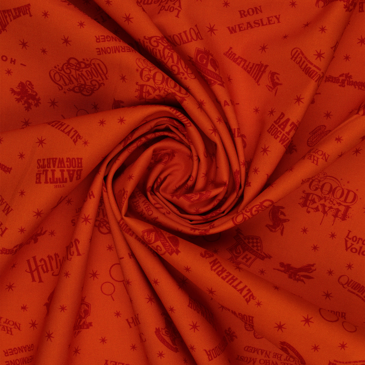 Orange Harry Potter fabric with rust-red words, Hogwarts house crests and scattered starbursts in a swirl.