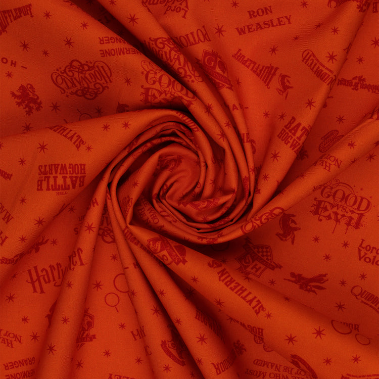Orange Harry Potter fabric with rust-red words, Hogwarts house crests and scattered starbursts in a swirl.