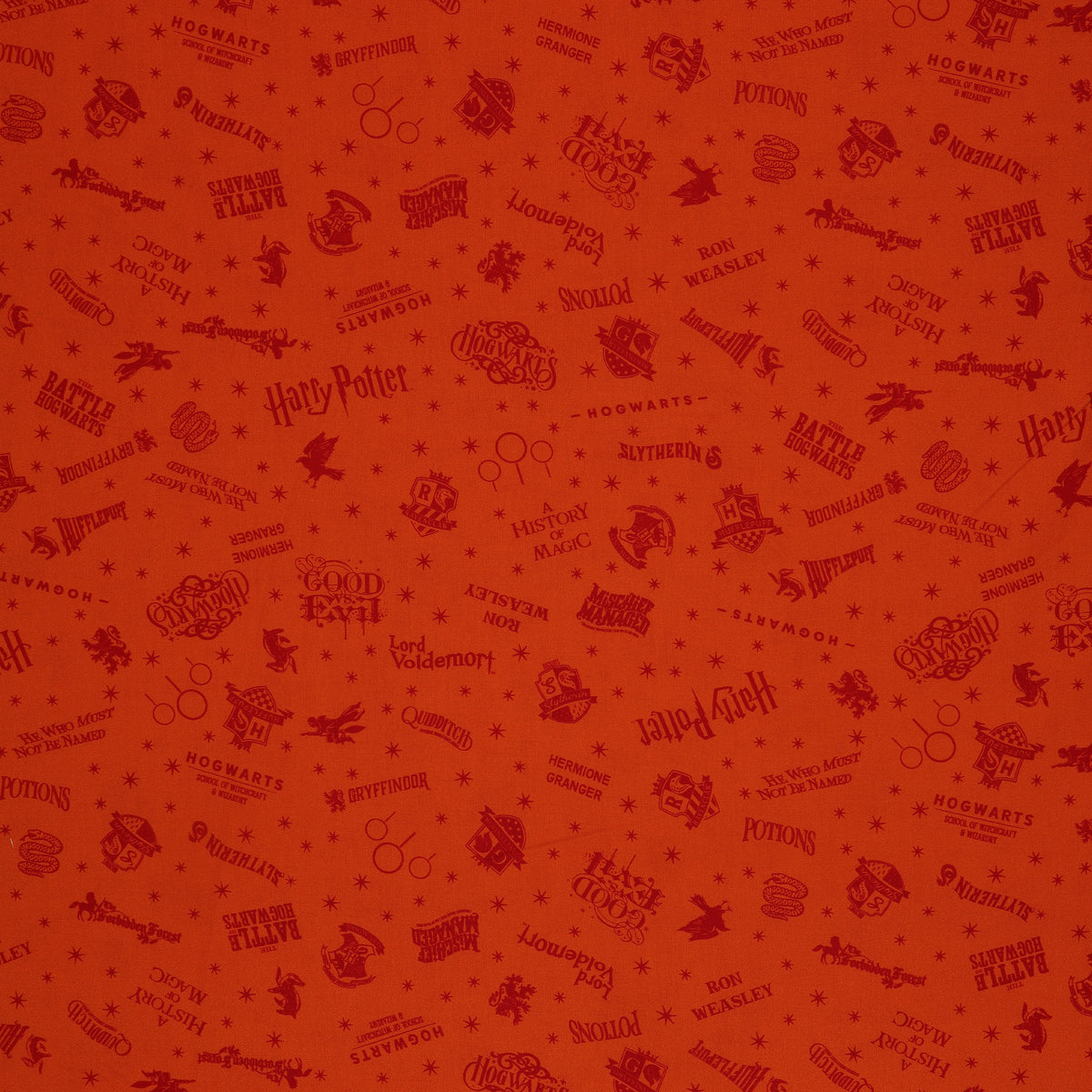 Orange Harry Potter fabric with rust-red words, Hogwarts house crests and scattered starbursts.