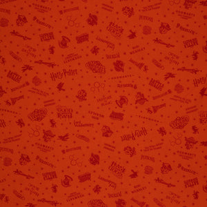 Orange Harry Potter fabric with rust-red words, Hogwarts house crests and scattered starbursts.