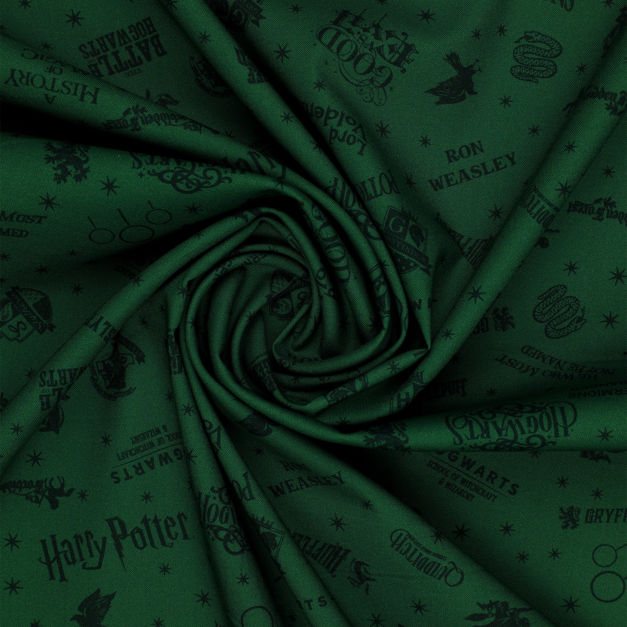 Dark green Harry Potter fabric with nearly black house crests, serpents, words and scattered stars in a swirl.