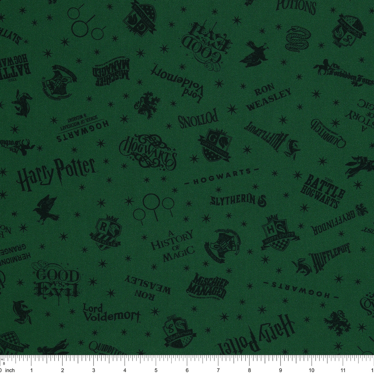 Dark green Harry Potter fabric with nearly black house crests, serpents, words and scattered stars with ruler for scale.