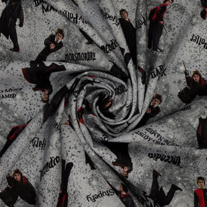 Gray Harry Potter fabric with wand-wielding figures, spell names, stars and smoky swirls in a swirl.