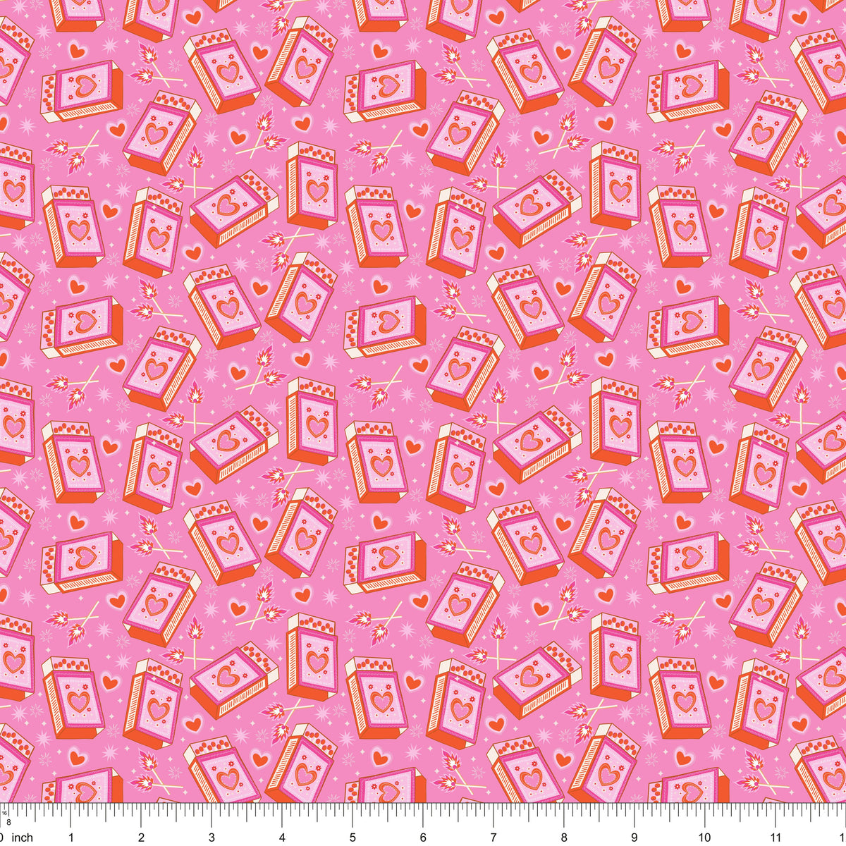 Pink fabric with tossed heart matchboxes and lit matches, shown with ruler for scale