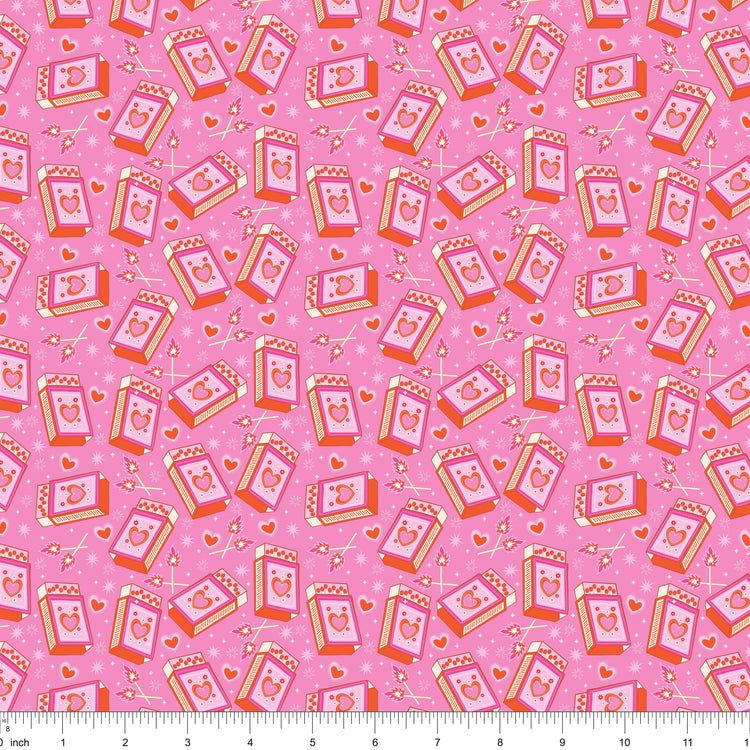 Pink fabric with tossed heart matchboxes and lit matches, shown with ruler for scale