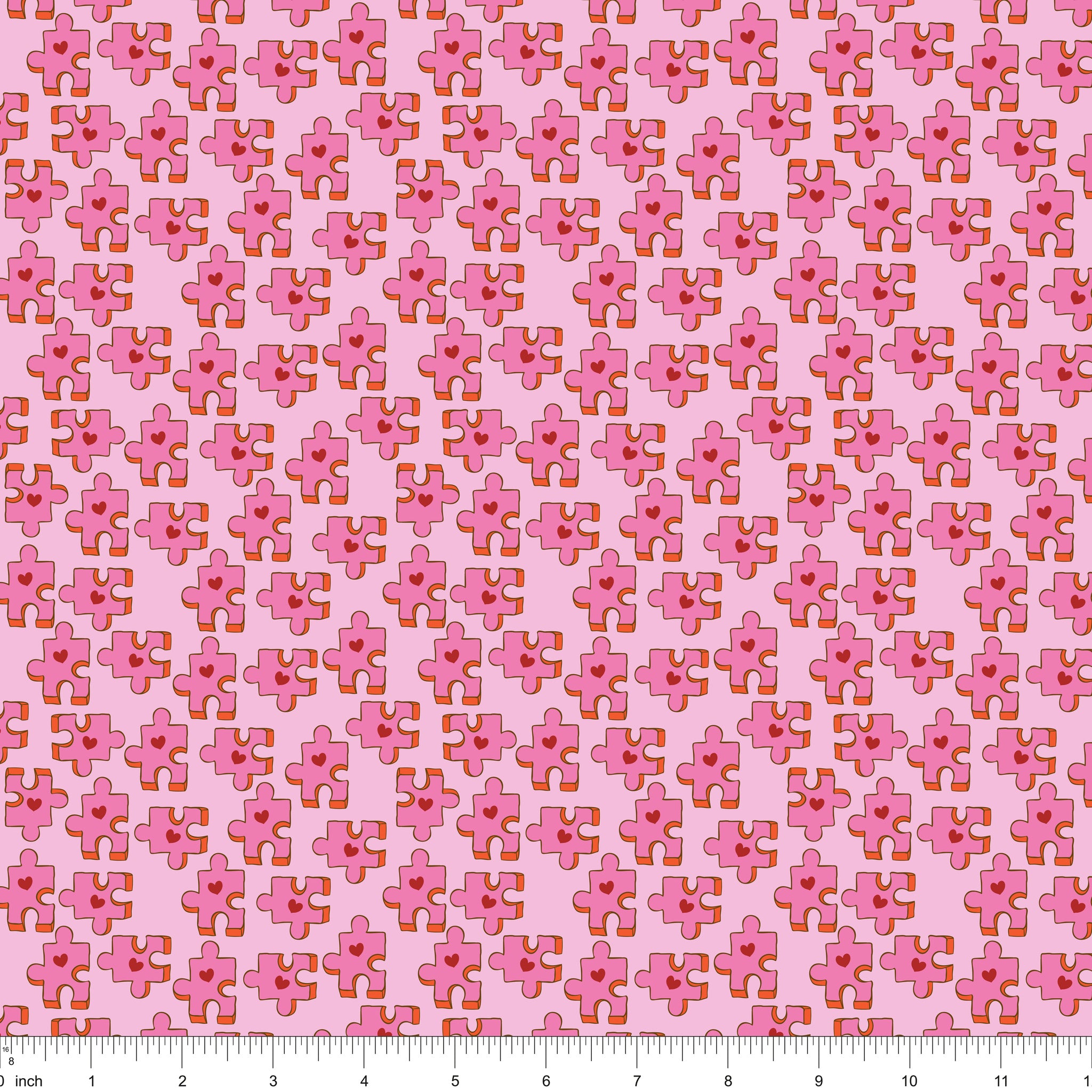 Pink fabric with puzzle pieces and red hearts, shown with ruler for scale