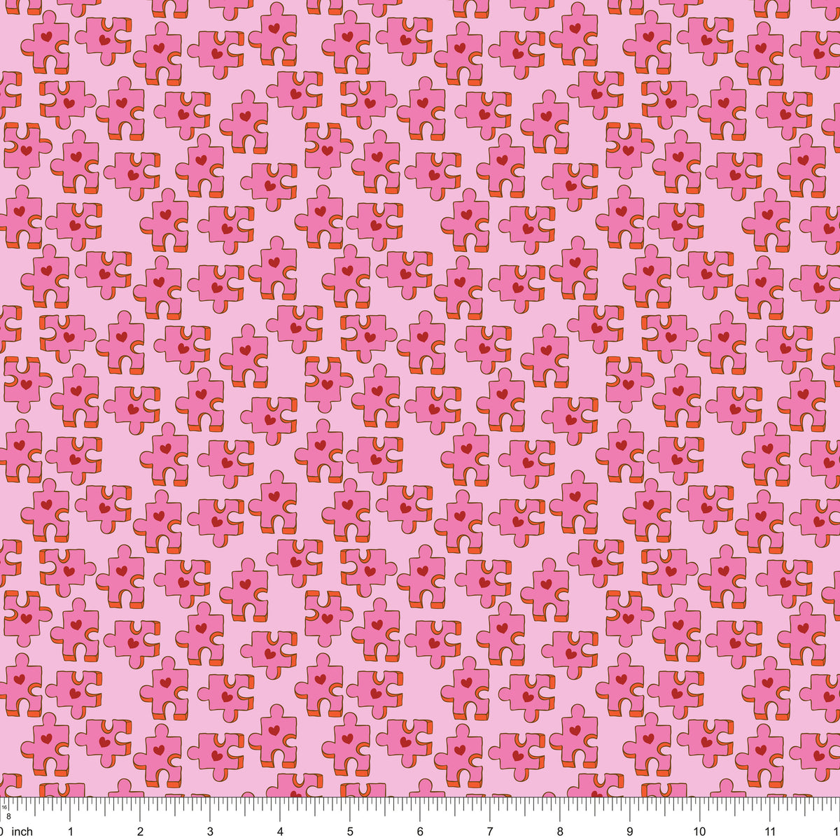 Pink fabric with puzzle pieces and red hearts, shown with ruler for scale