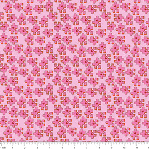 Pink fabric with puzzle pieces and red hearts, shown with ruler for scale