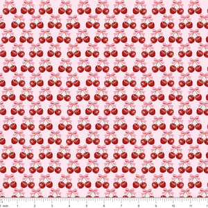 Light pink fabric with red cherries tied with pink bows, shown with ruler for scale