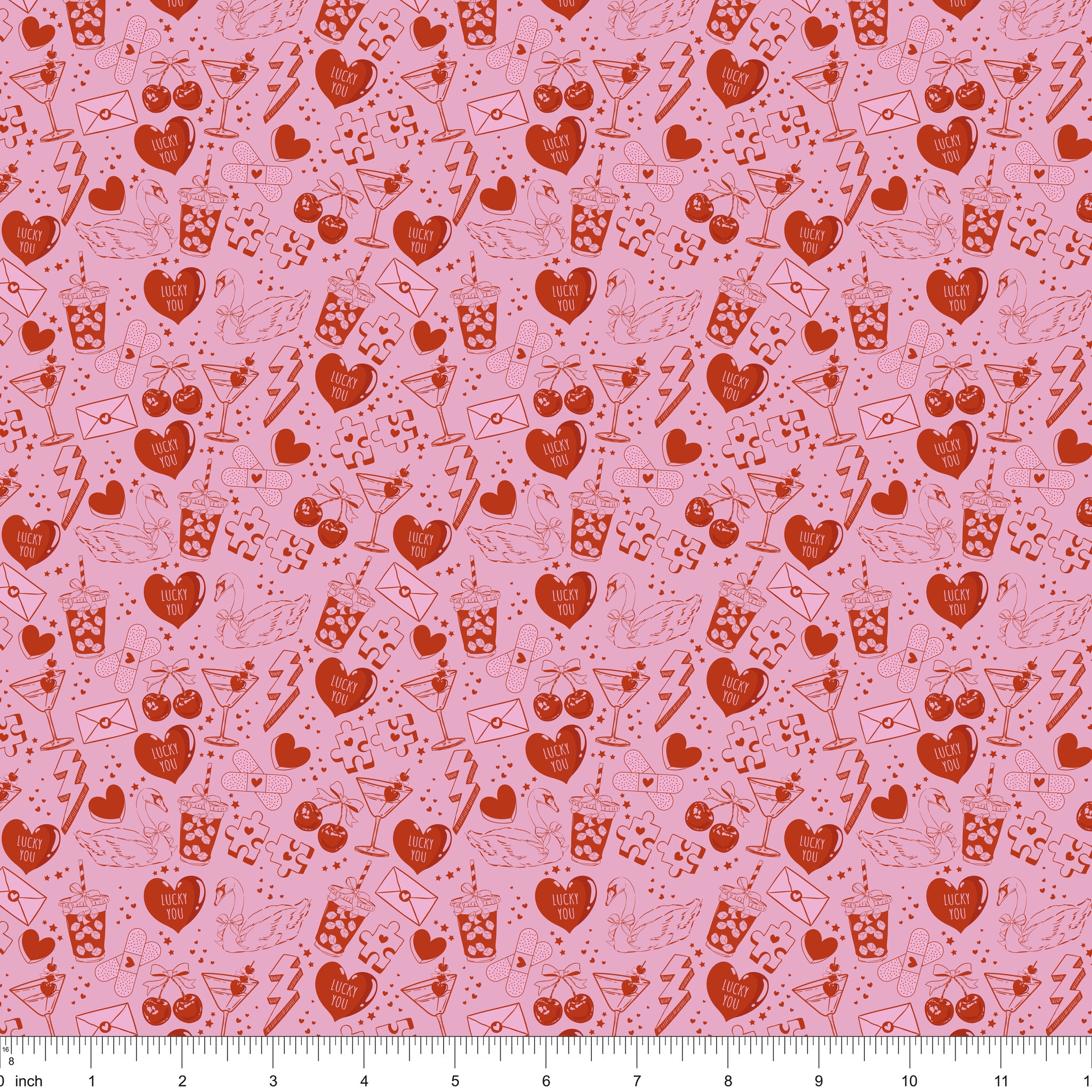 Pink fabric with red line drawings of hearts, swans, cocktails and Lucky You candy hearts, shown with ruler for scale
