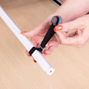 A close-up of a person's hands with orange glitter nail polish attaching a black elastic strap to a white bar.