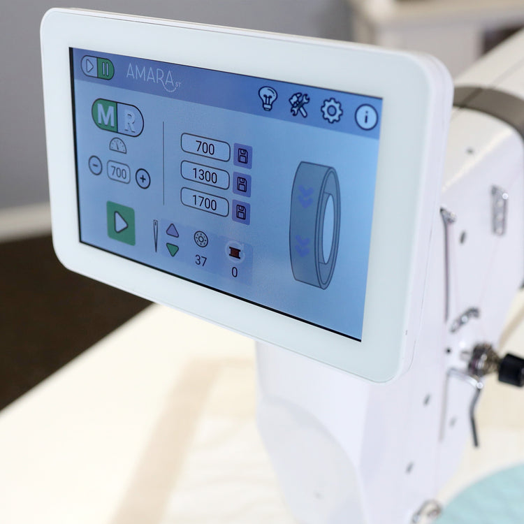 Close-up of a white AMARA sewing machine featuring a large touchscreen display with interface controls and settings.