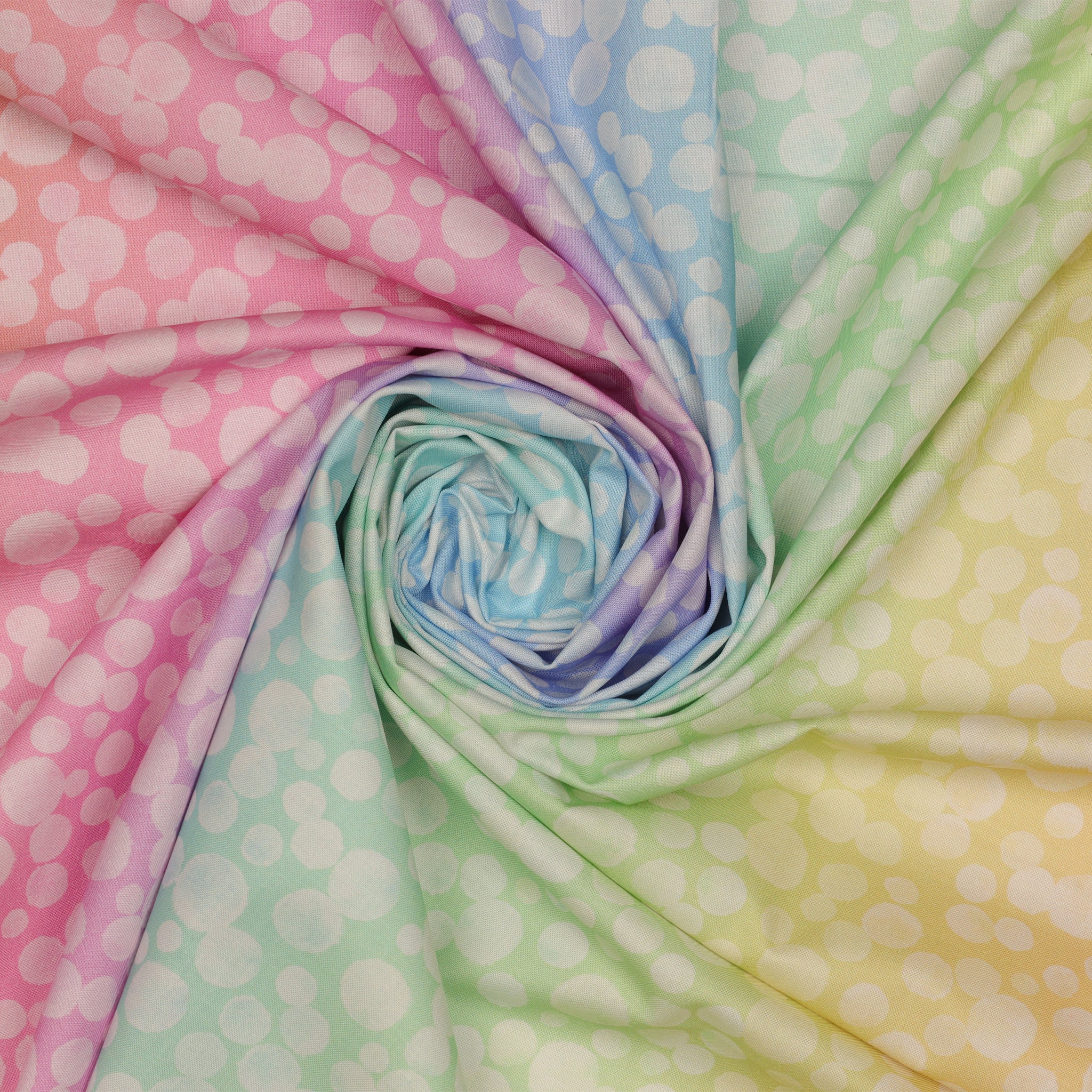 Bumbleberries Pastel Rainbow fabric arranged in a spiral, showcasing scattered white dots against softly blended pastel shades of pink, blue, lavender, mint, and yellow.