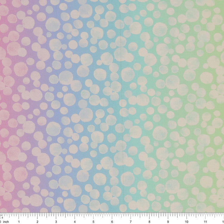 Bumbleberries Pastel Rainbow fabric with densely scattered white watercolor dots over a pastel ombre background transitioning through peach, pink, lavender, aqua, mint, and yellow. Ruler for scale. 