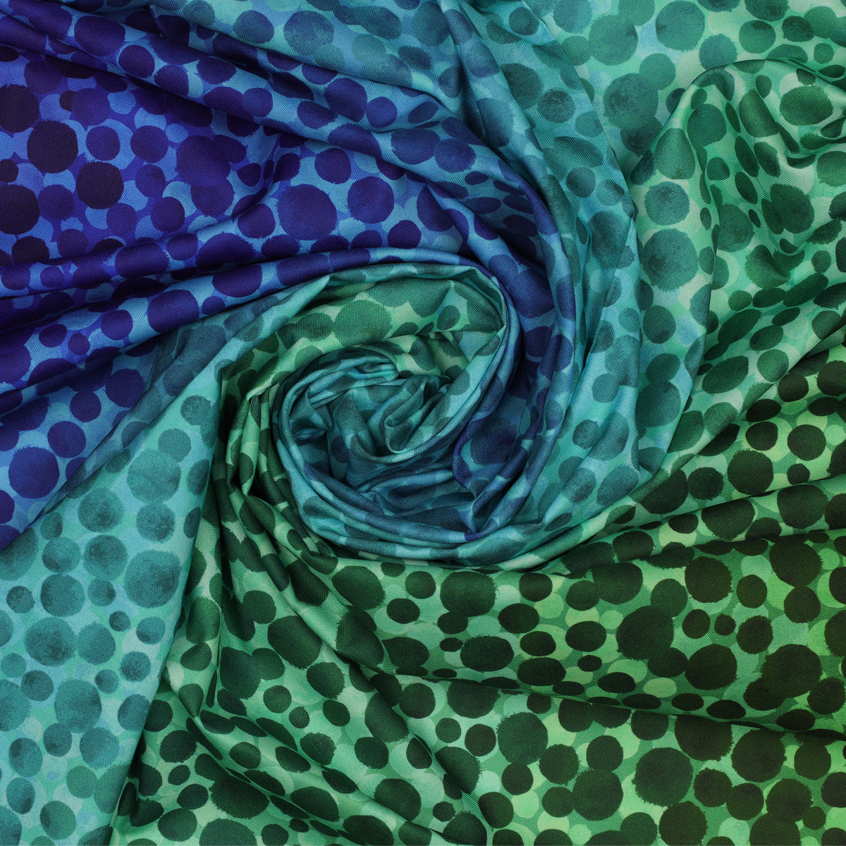 Bumbleberries Ocean fabric arranged in a spiral, showcasing varying sizes of blue, aqua, and green dots across a vibrant ocean-inspired gradient.