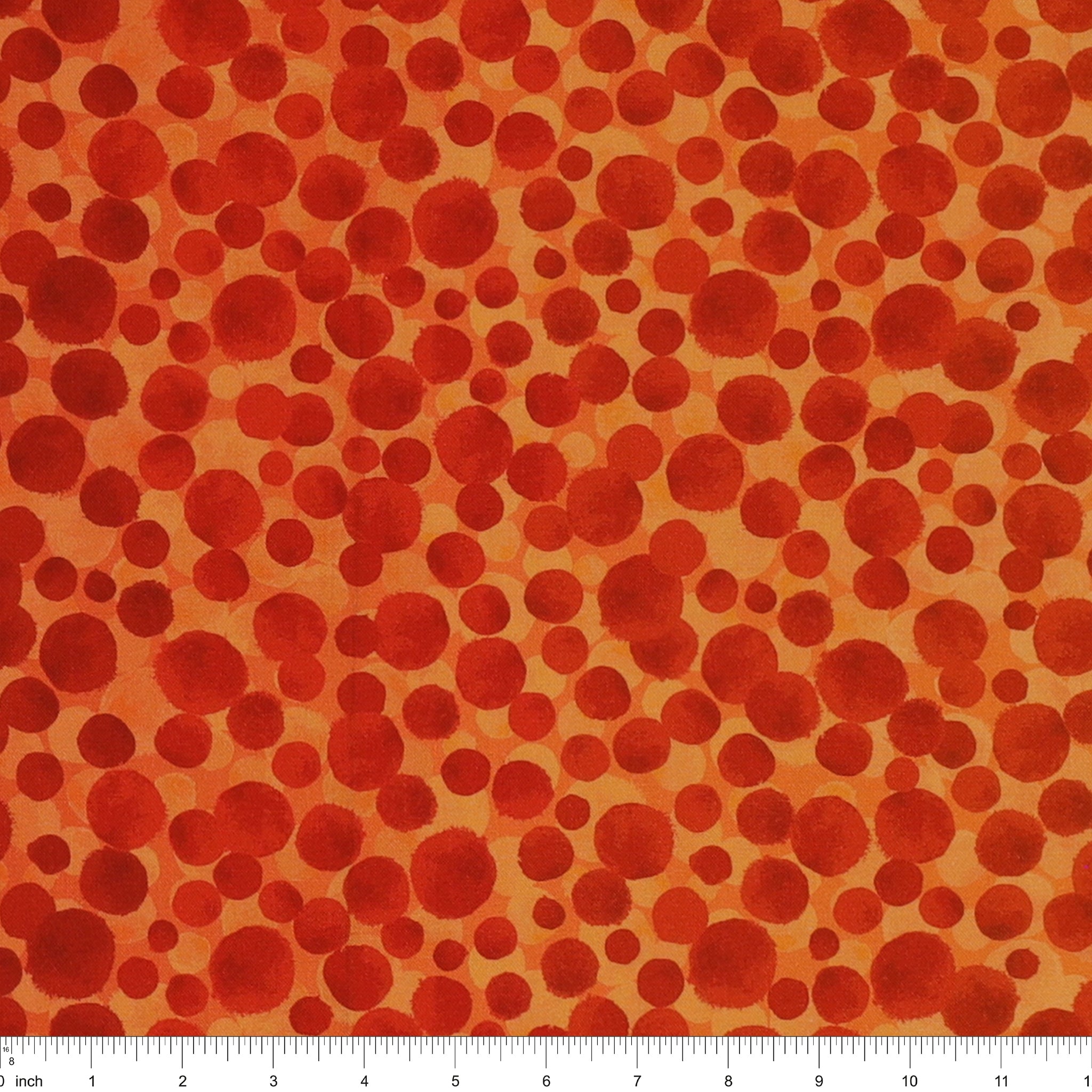 Bumbleberries Flame fabric with irregular red and rust-colored dots in varying sizes against a bright orange background and a ruler for scale. 