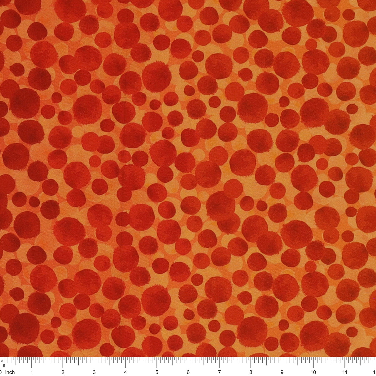 Bumbleberries Flame fabric with irregular red and rust-colored dots in varying sizes against a bright orange background and a ruler for scale. 