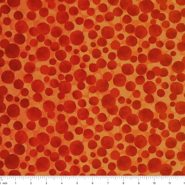 Bumbleberries Flame fabric with irregular red and rust-colored dots in varying sizes against a bright orange background and a ruler for scale. 