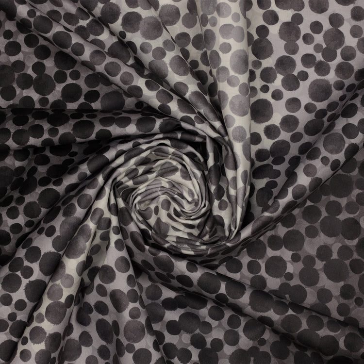 Bumbleberries Black to White fabric gathered in a spiral, showcasing irregular black and gray dots in varying sizes.