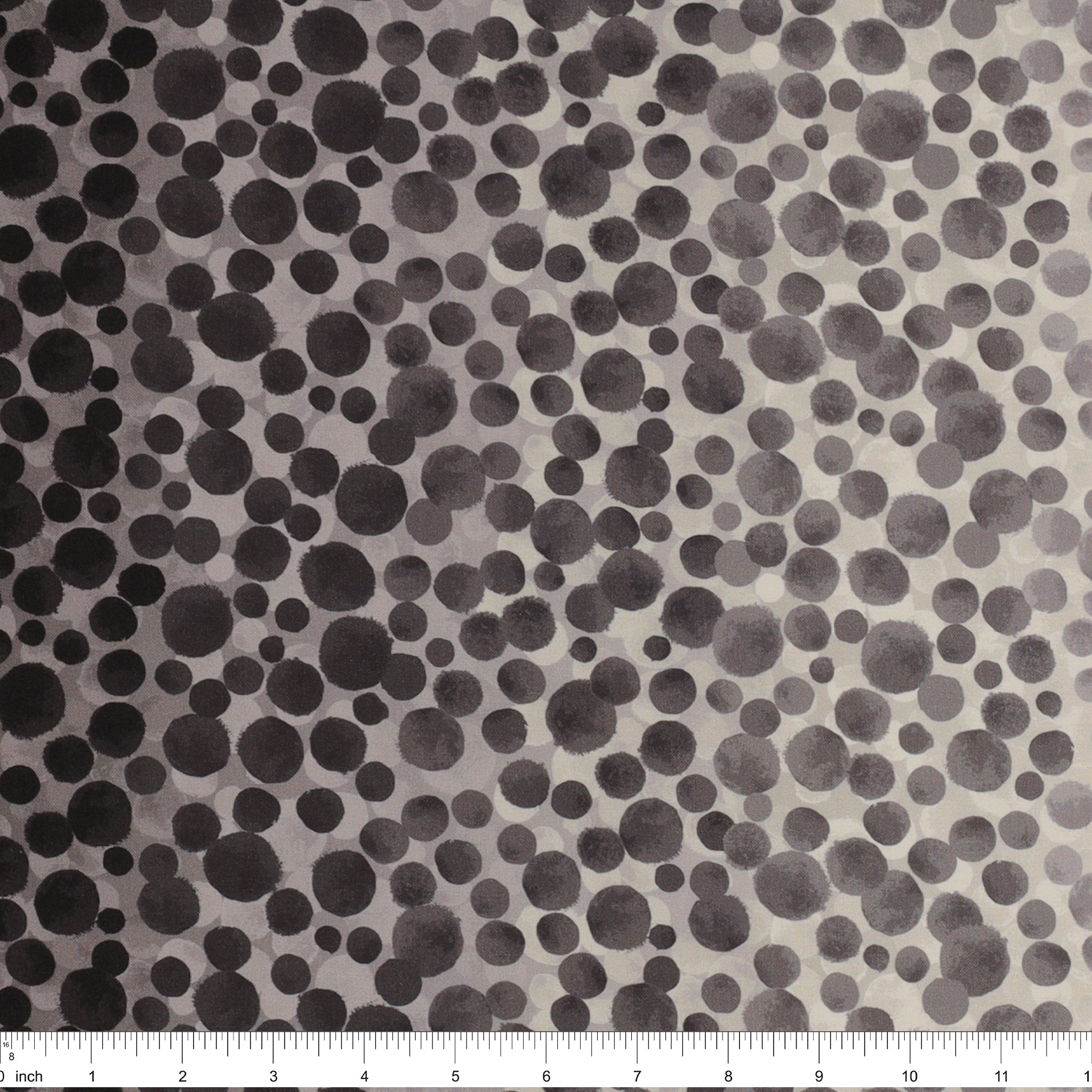 Bumbleberries Black to White fabric with a dense dotted pattern that gradually transitions from black along the edges to lighter gray and white toward the center, ruler for scale.
