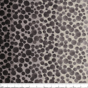 Bumbleberries Black to White fabric with a dense dotted pattern that gradually transitions from black along the edges to lighter gray and white toward the center, ruler for scale.