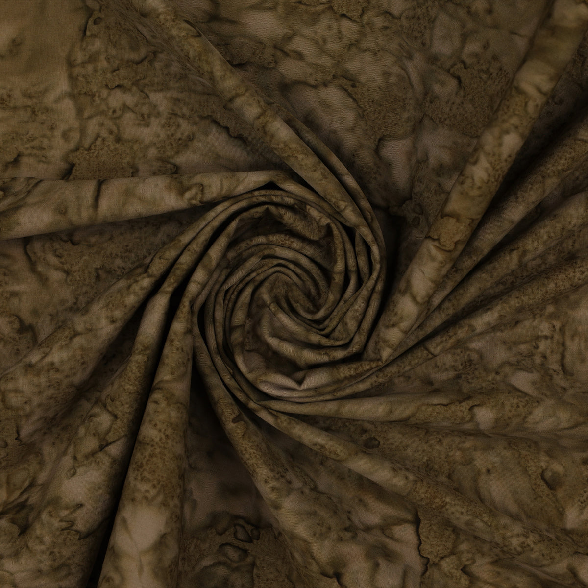 A close-up of draped fabric with a mottled, marbled pattern in earthy brown and beige tones, arranged in a spiral fold.
