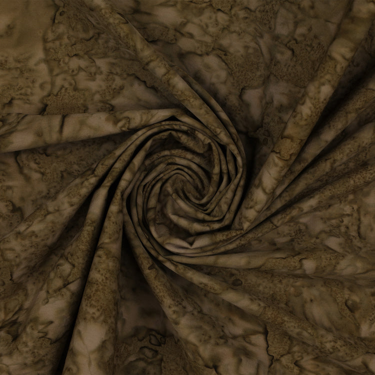 A close-up of draped fabric with a mottled, marbled pattern in earthy brown and beige tones, arranged in a spiral fold.