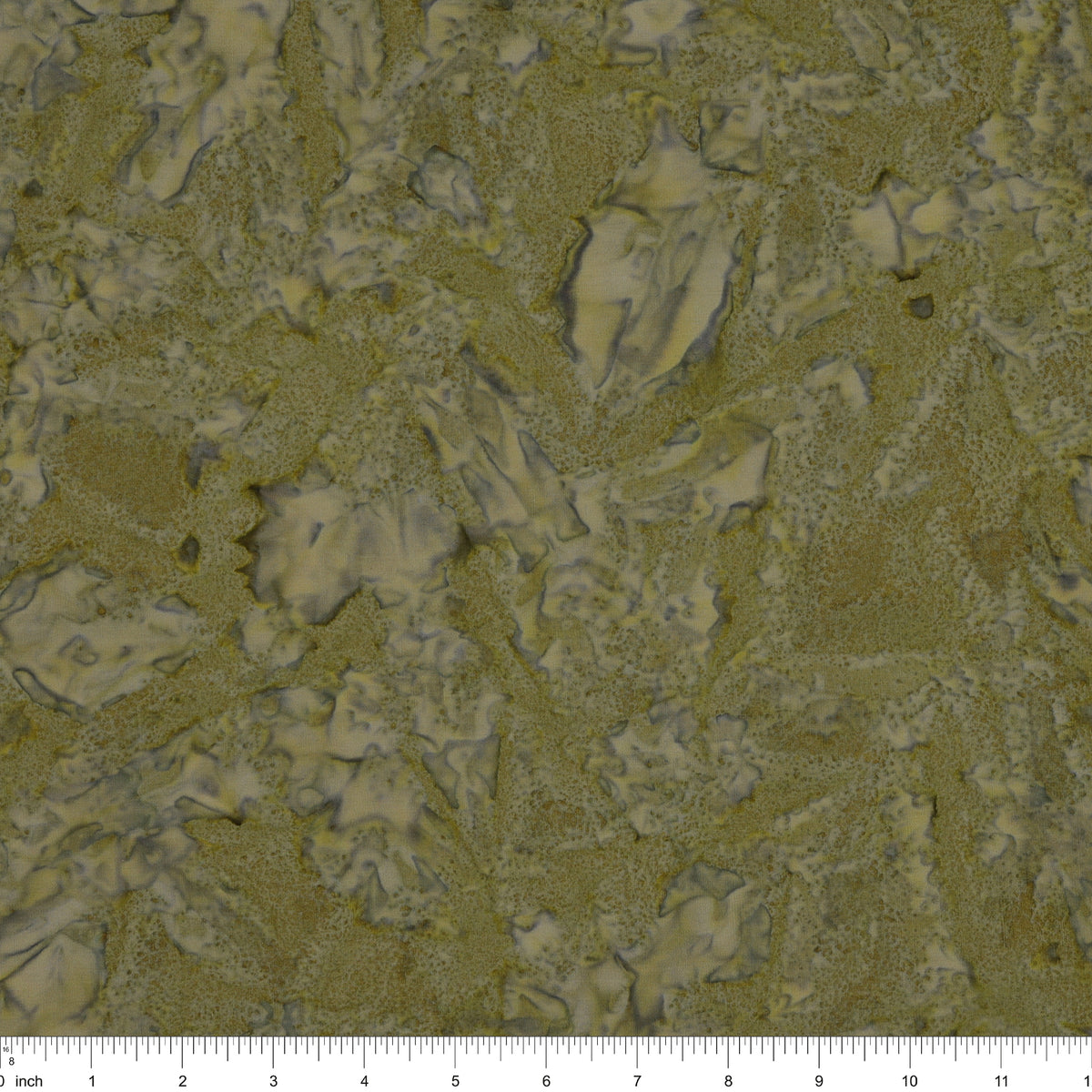 A close-up of fabric in muted olive green and beige tones, with a ruler scale visible along the bottom edge.