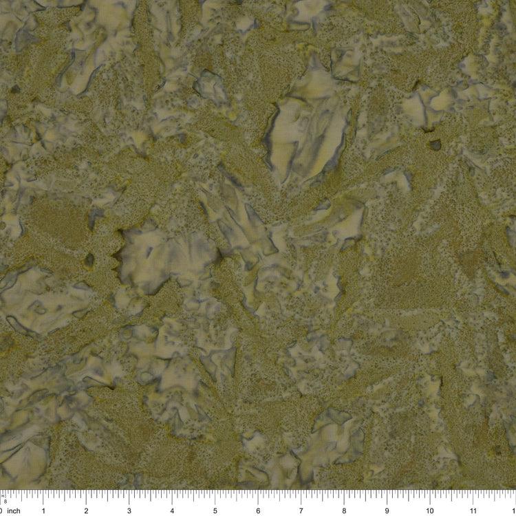 A close-up of fabric in muted olive green and beige tones, with a ruler scale visible along the bottom edge.