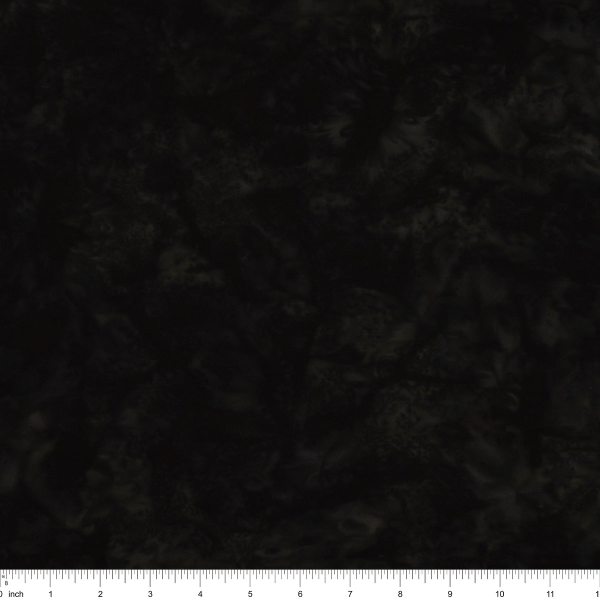 A close-up of a dark, mottled fabric texture with a white inch ruler along the bottom edge for scale.