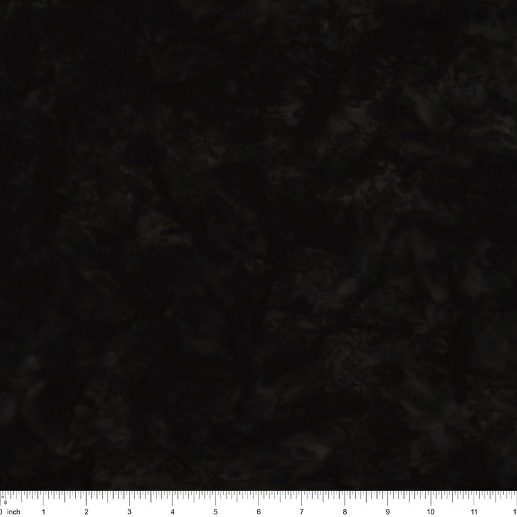 A close-up of a dark, mottled fabric texture with a white inch ruler along the bottom edge for scale.